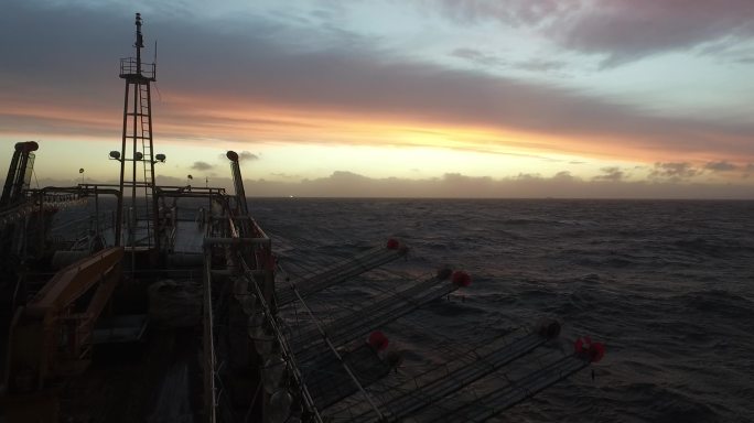 大西洋上迎着晚霞航行的远洋渔船船头