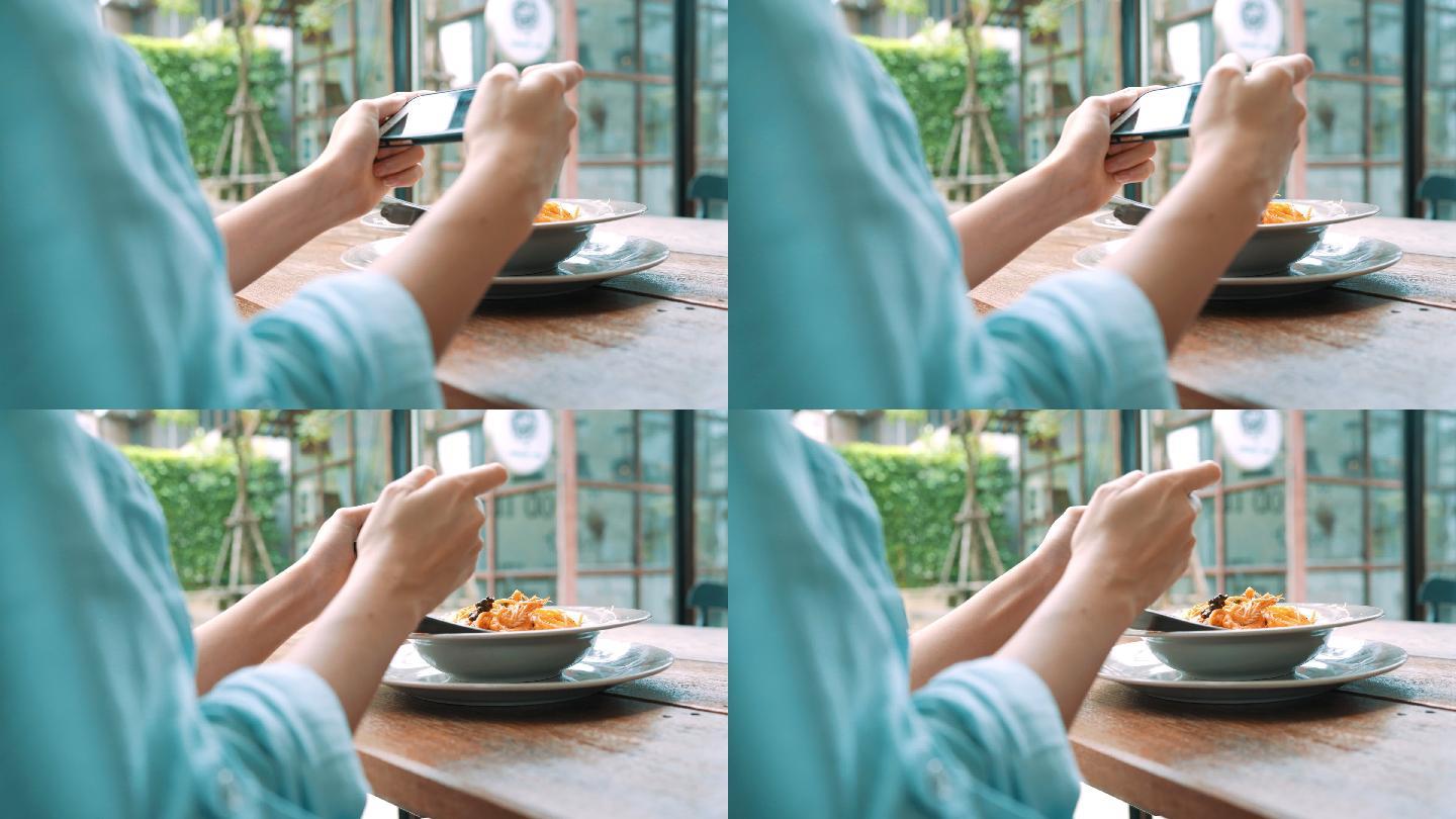 女子用手机在餐厅里拍摄午餐。