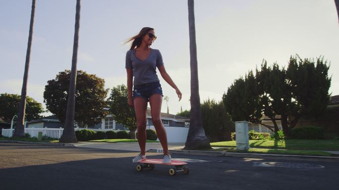 女孩在日落时沿街滑滑板