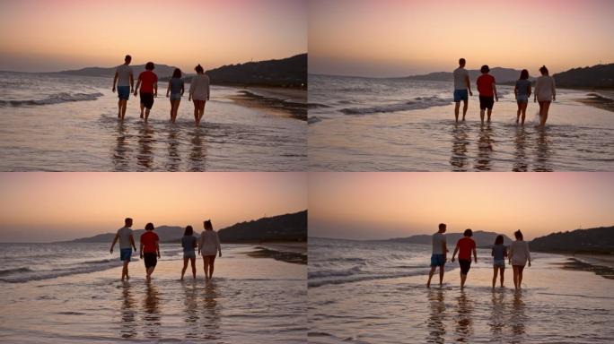 日落时，父母和两个孩子在海滩上散步