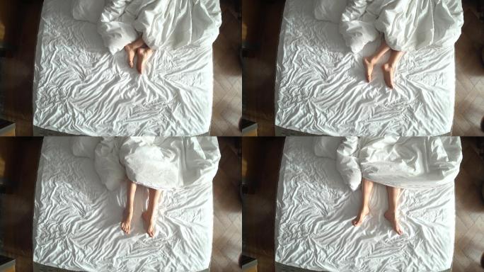 从上方看床上的女性腿，白色床上用品