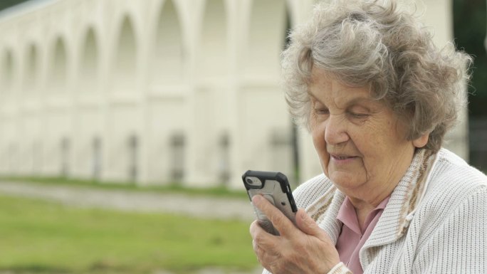 老妇人用智能手机和朋友聊天