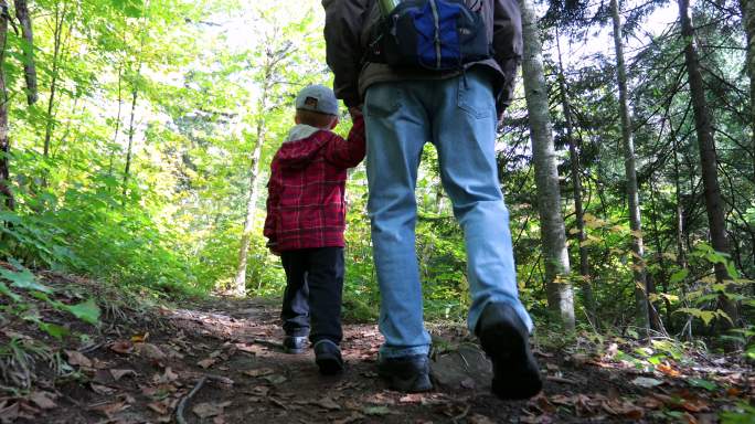 爷爷和孙子在秋天的徒步小道上探索森林