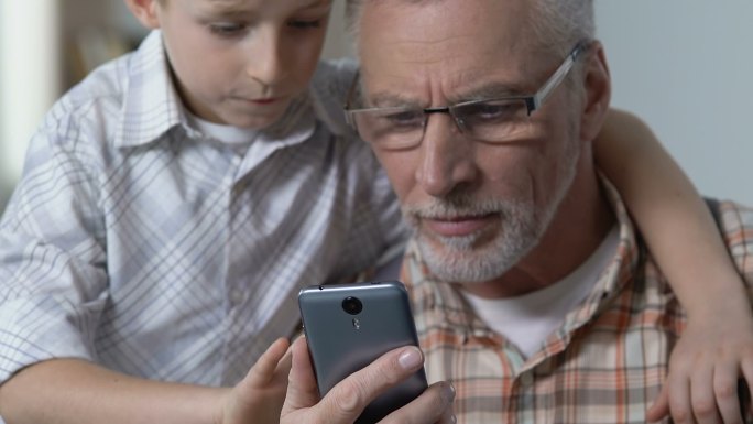 学童向祖父展示如何使用智能手机