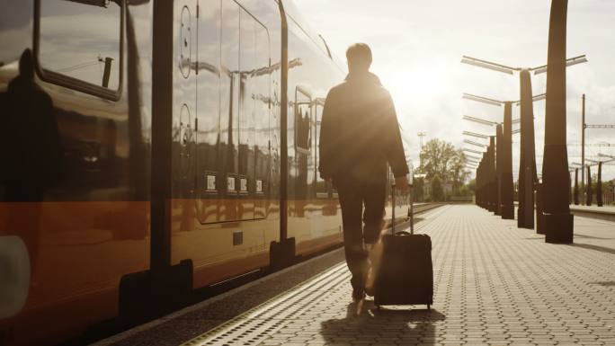 日落时分，带着行李的男子在火车站上行走