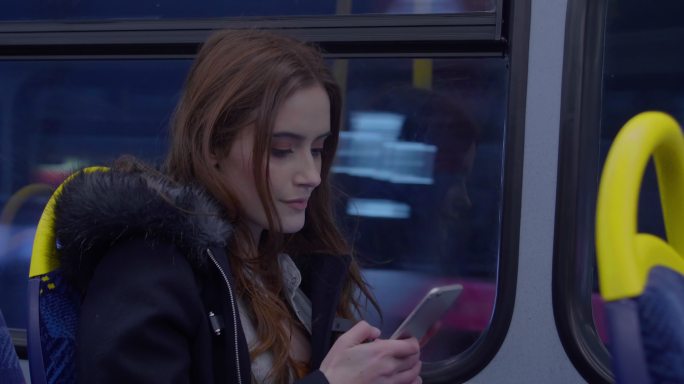 女生在巴士上用智能手机