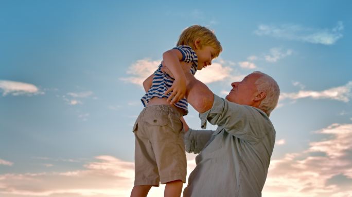 爷爷在阳光下把孙子抱起来