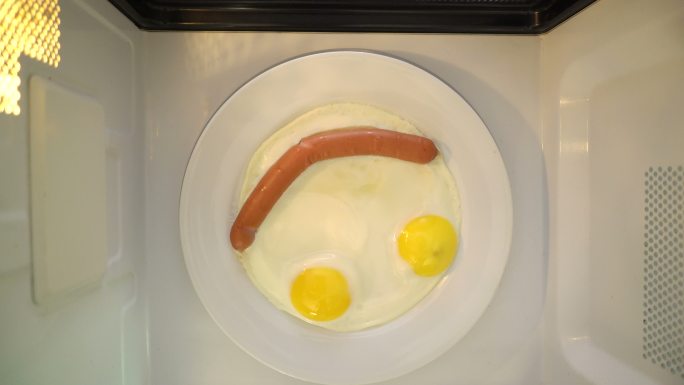 制作早餐。煎蛋和香肠组成笑脸