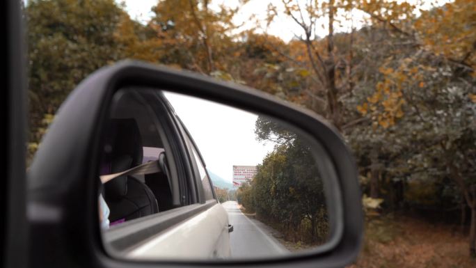 秋天行驶在公路上的汽车倒车镜视角