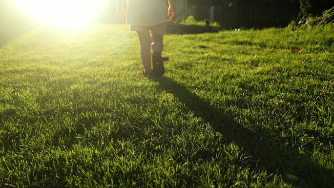 小女孩在草地上慢慢走向太阳