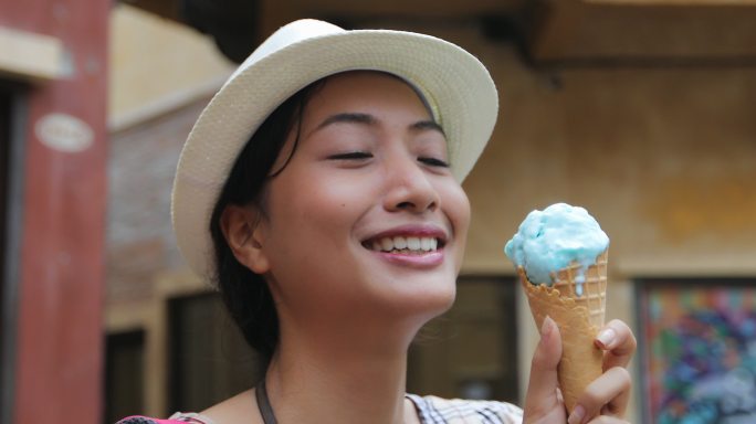 美丽的女游客在暑假戴着帽子吃着冰激凌