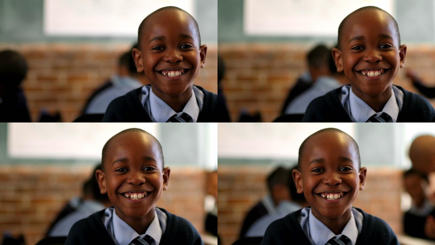 在学校的教室里，一个男生在看摄像机微笑