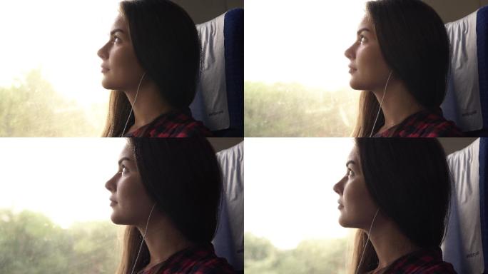 忧郁的女孩乘火车旅行。坐在窗户旁边