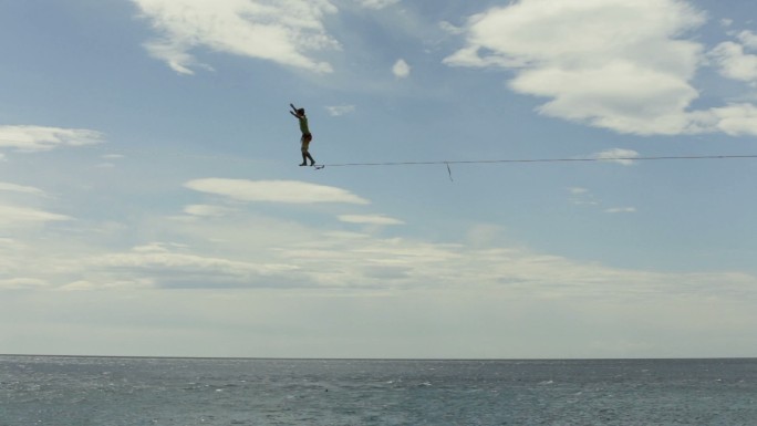 运动员在海洋上沿着高架线保持平衡地行走