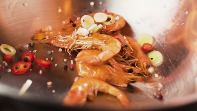香料和虾仁以慢动作落入锅中。