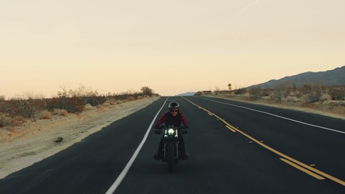 骑着摩托车在日落时举起双臂庆祝