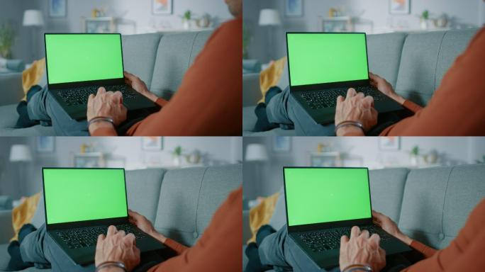 在沙发上玩绿屏笔记本电脑