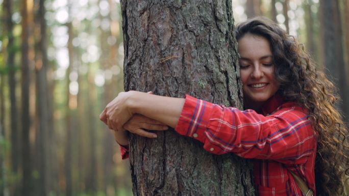 年轻女子抱着大树树干