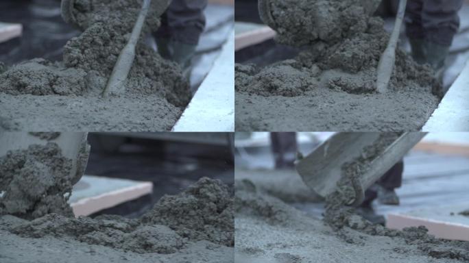 工人用铲子平整施工现场地板上的混凝土