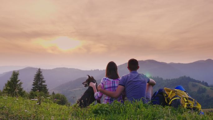 在欣赏风景的夫妇背影眺望远望山顶美景夕阳