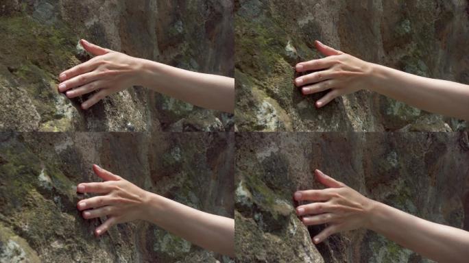 女性手触摸岩石粗糙表面。