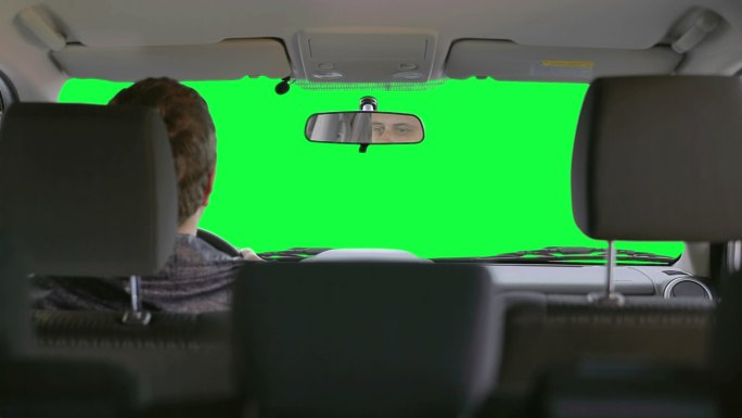 一名男子在绿色背景下驾驶汽车