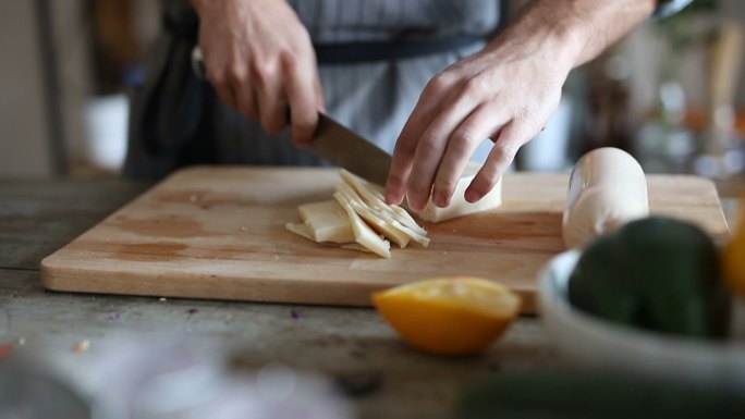 男人用菜刀在砧板上切奶酪或黄油