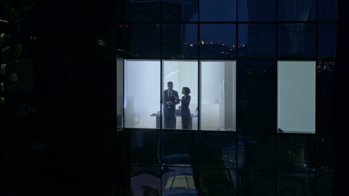 两个人站在办公室窗户前交谈