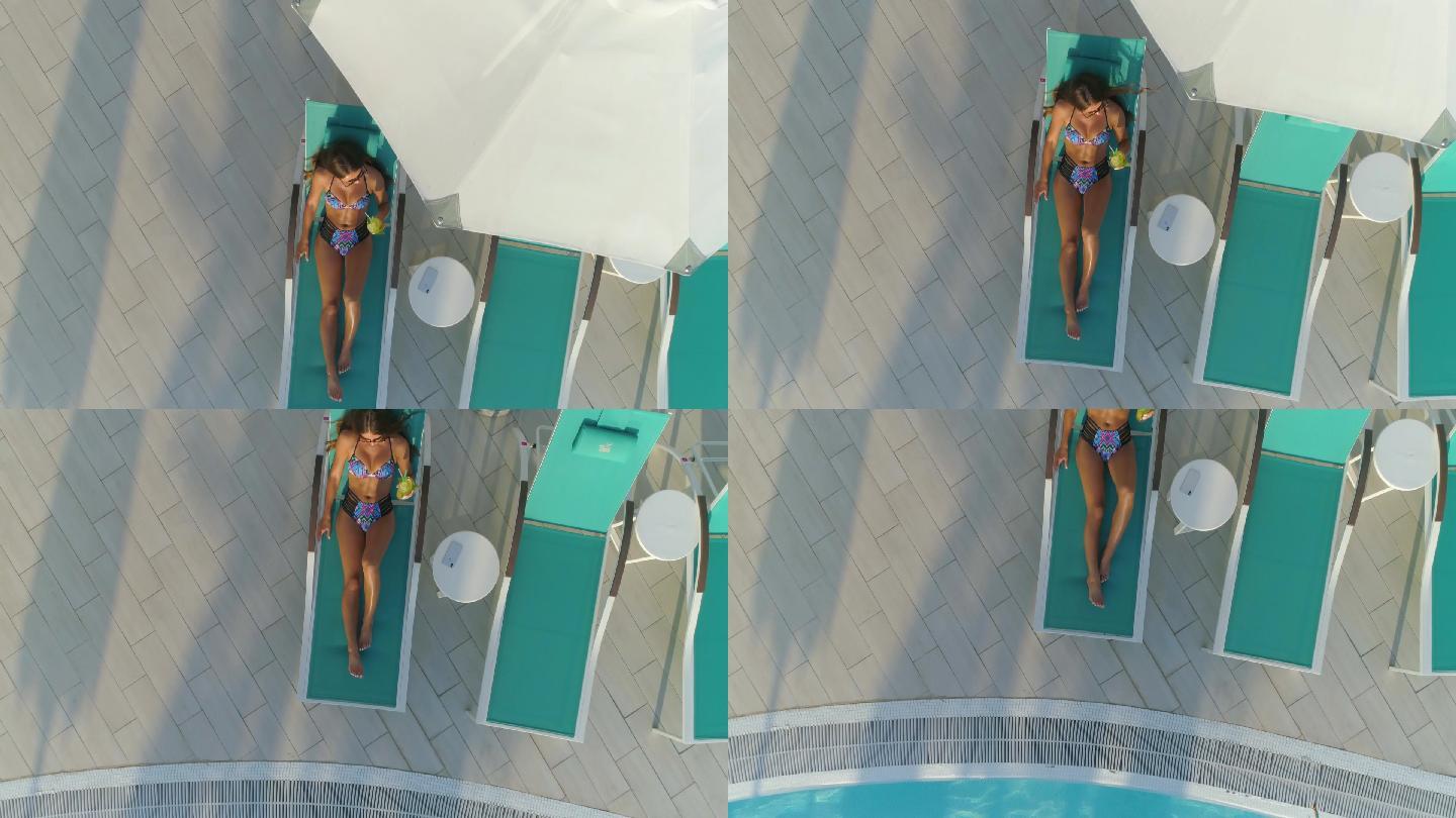女孩躺在泳池边的躺椅上