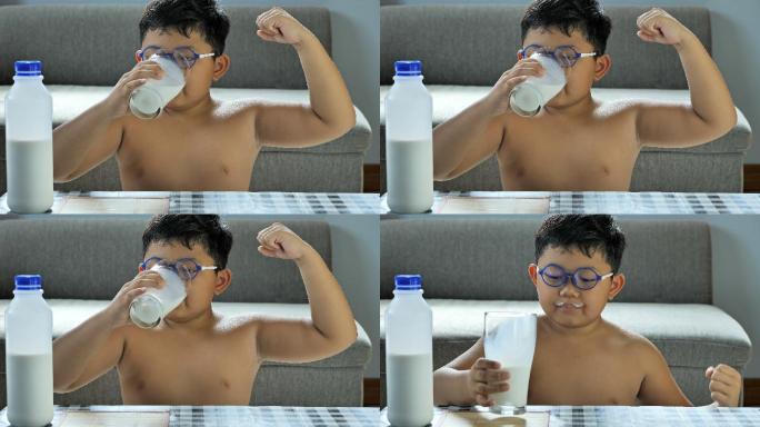 小男孩喝了牛奶后，展示他的二头肌的力量