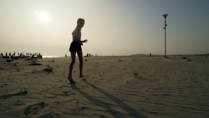 一个小男孩在空沙滩上逃跑的长途跋涉追逐