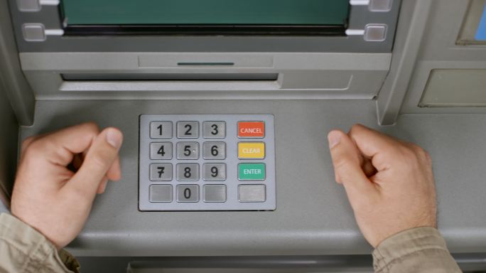 手插入银行卡并在ATM键盘上输入密码