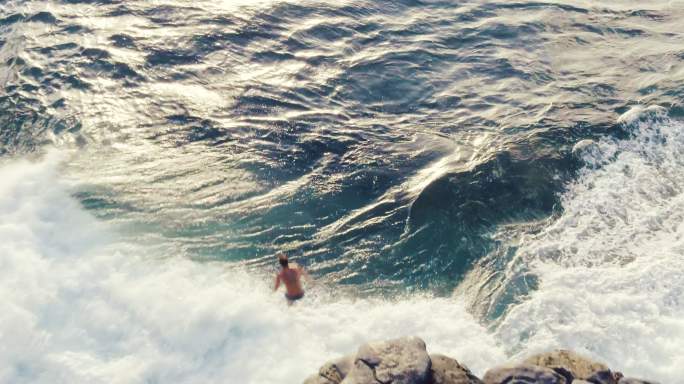 年轻人从海上悬崖上跳下