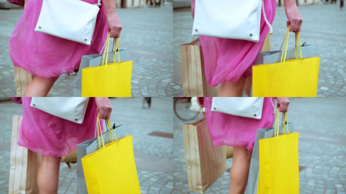 穿着粉色连衣裙的女士拿着购物袋散步