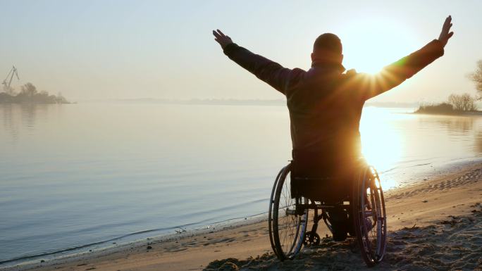 轮椅上的男子夕阳希望轮椅上的残疾人打气加