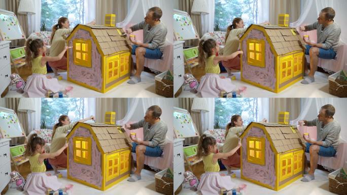 父母陪女儿一起建造和粉刷玩具纸板房子