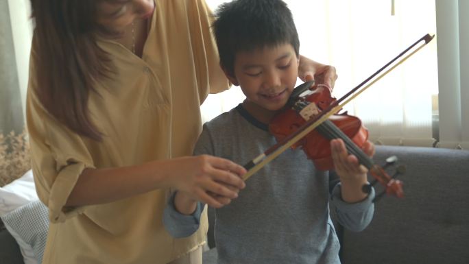 快乐的小男孩在家学习拉小提琴