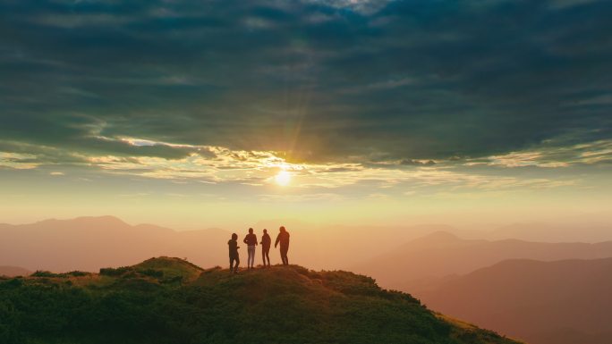 四个人在山上跳舞，伴随着美丽的日落