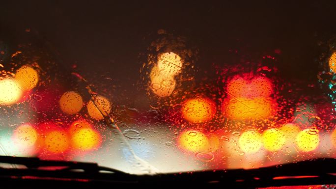 下雨天车窗外的车尾灯光，汽车雨刮器
