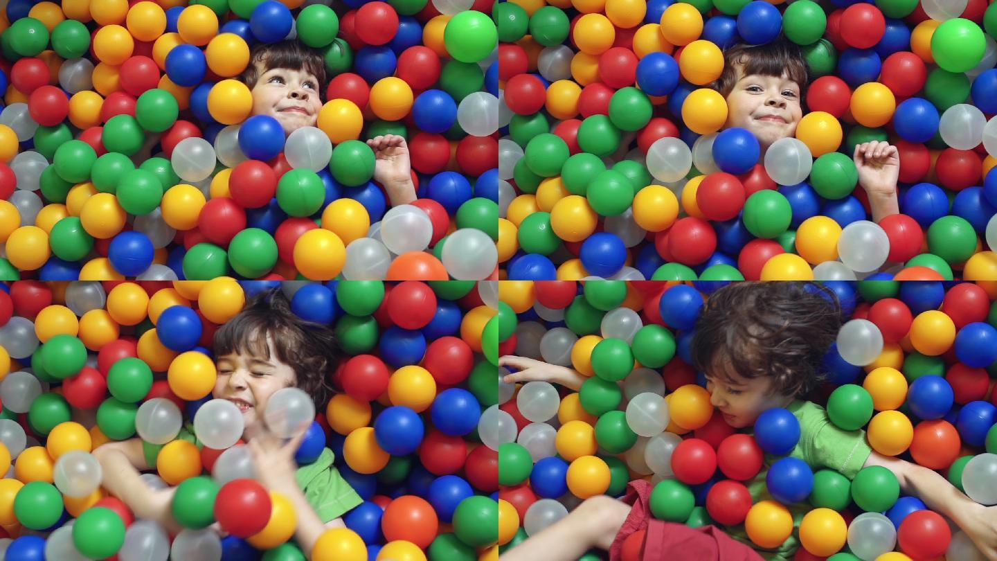 小男孩躺在一堆五颜六色的塑料球里