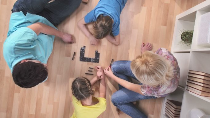 一个家庭在客厅的木地板上玩多米诺骨牌