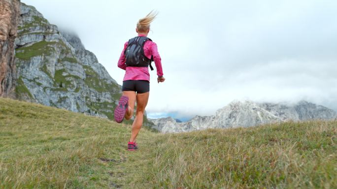 女运动员穿越高山上的草地
