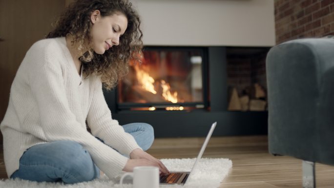 坐在壁炉前使用笔记本电脑的女人