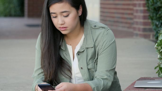 女大学生在手机上读到令人沮丧的新闻