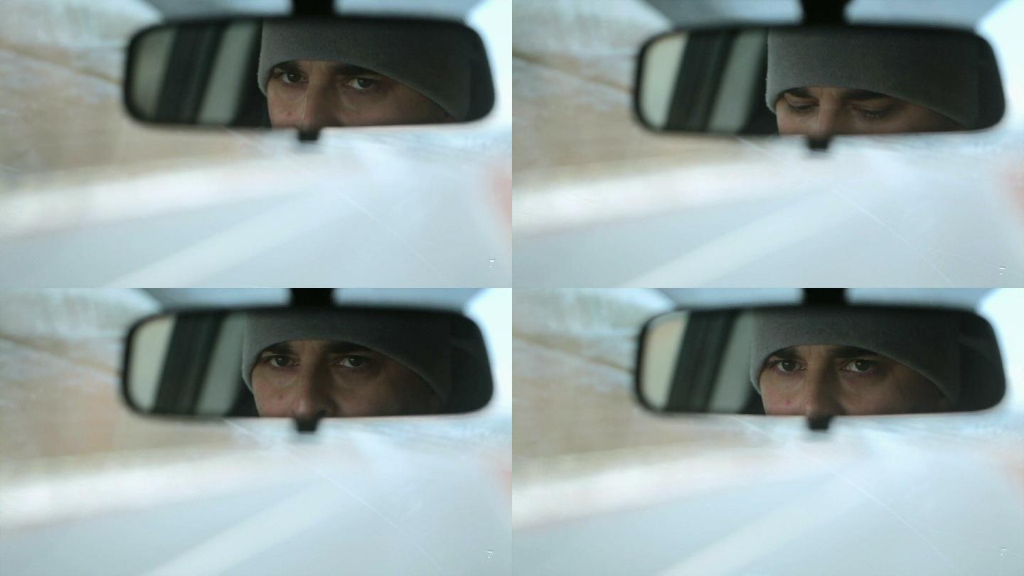 从汽车后视镜中反射男性面部。