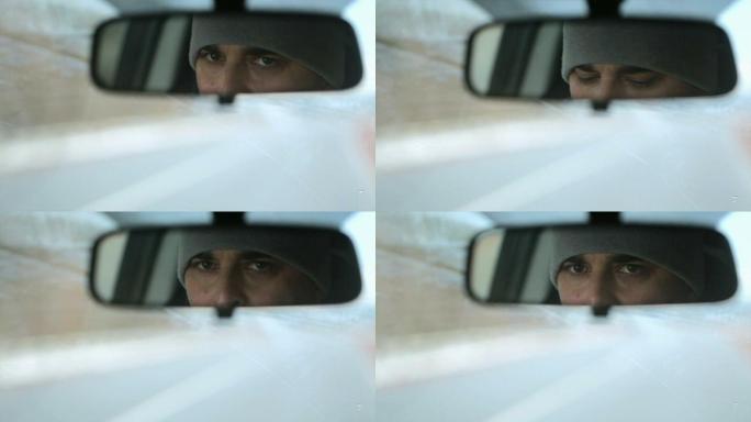 从汽车后视镜中反射男性面部。