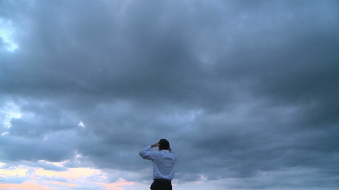 一个商人站在山顶，看着乌云密布的天空呐喊