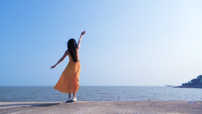 长发女生朝着大海挥手告别