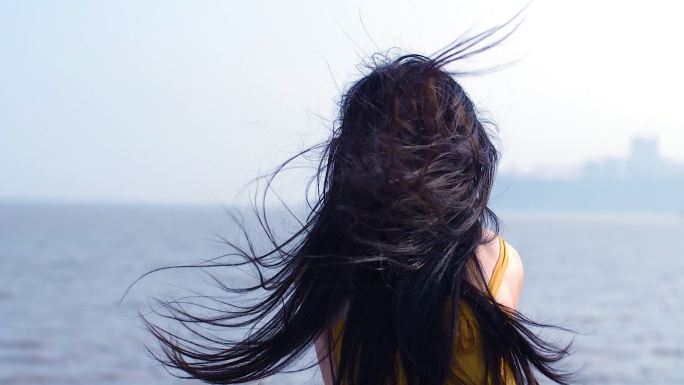 女孩在海边吹风背影，头发发丝飞扬