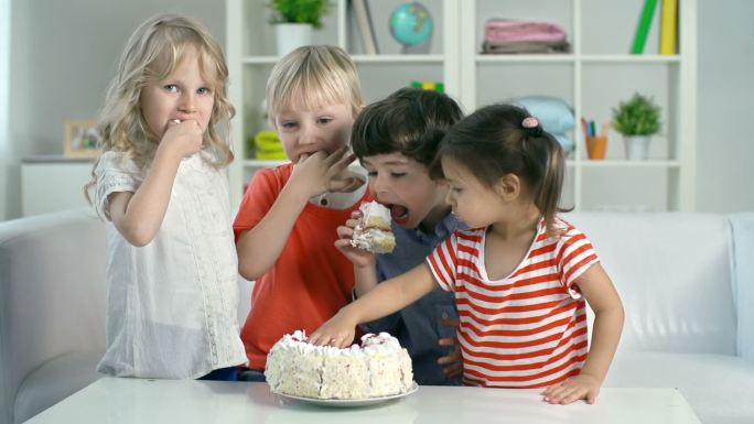 四个孩子用手吃生日蛋糕